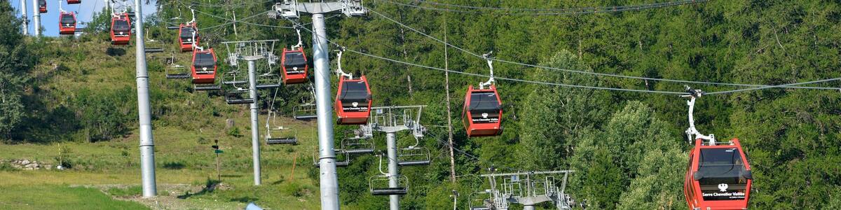 A cable car system with red gondolas ascending a mountain.