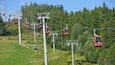 Eine Seilbahn mit roten Gondeln, die einen Berg hinauffährt.