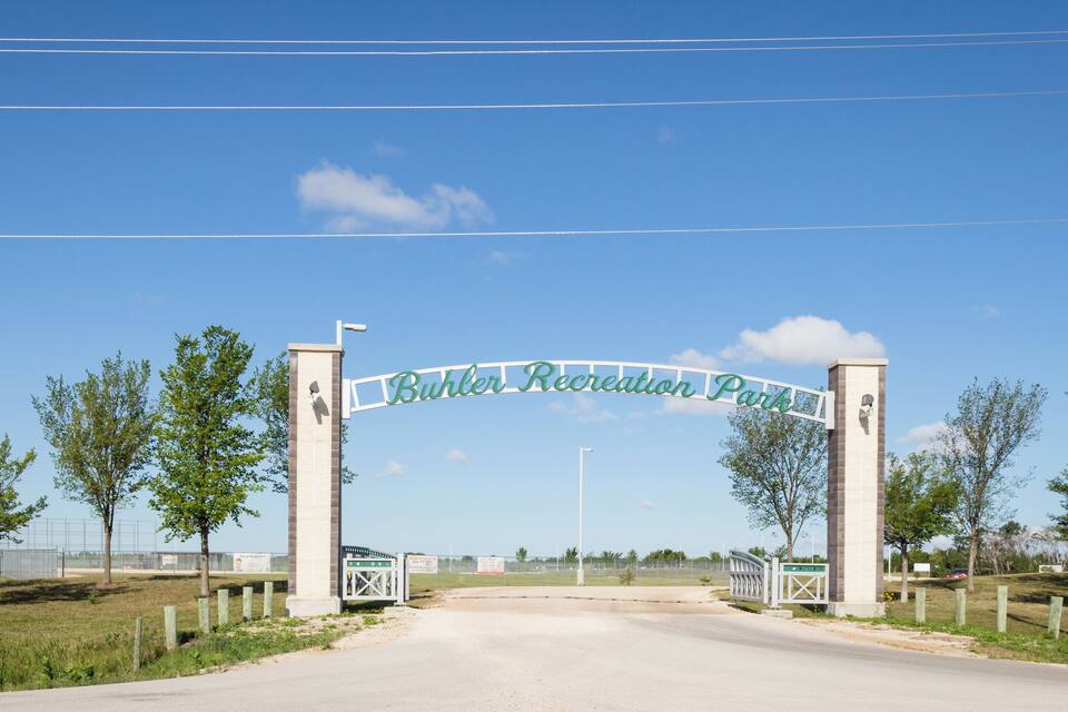 Carretera que conduce al parque recreativo Buhler, con cielo azul despejado y árboles a ambos lados.