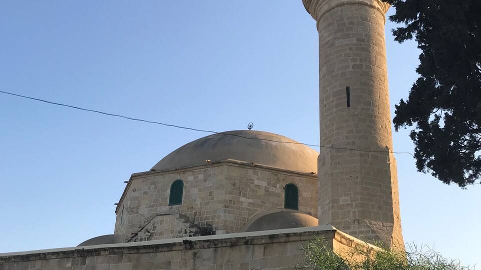 A historic mosque with a prominent minaret and arched entrance.