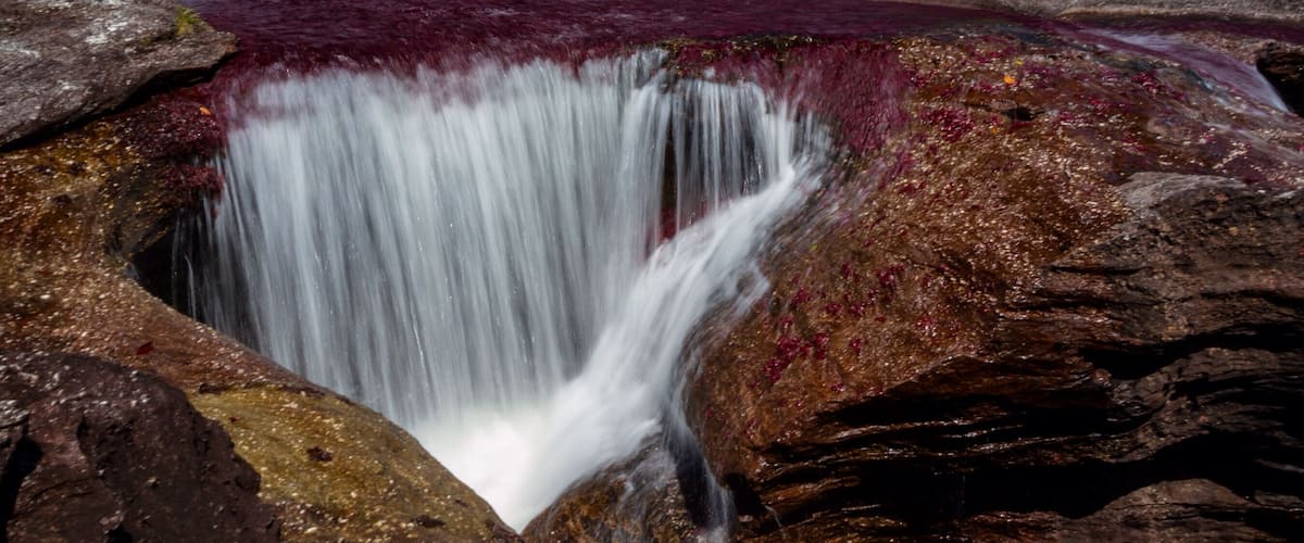 A waterfall cascading over rocks with a reddish-brown hue.