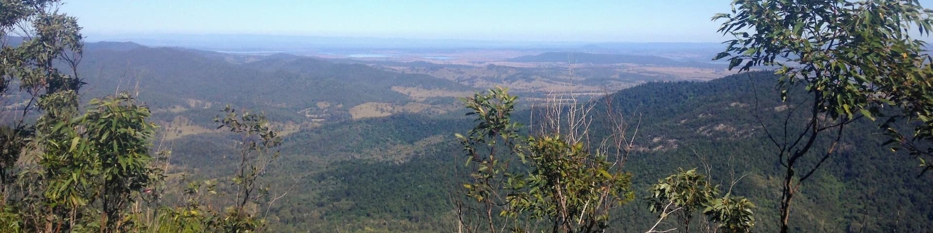 A mountainous landscape with dense forests and a clear blue sky.