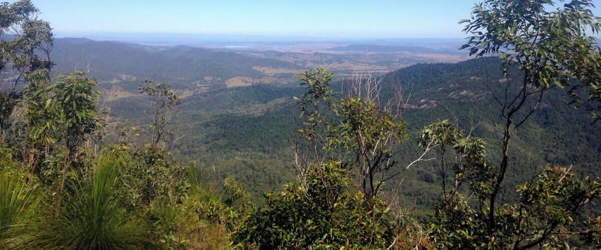 A mountainous landscape with dense forests and a clear blue sky.