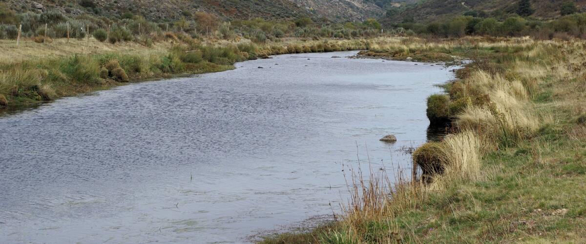 A river winding through a hilly landscape with sparse vegetation.