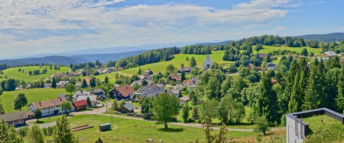 A rural village nestled in a valley with green fields and scattered houses.