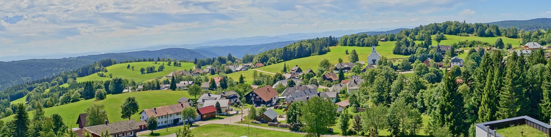 A rural village nestled in a valley with green fields and scattered houses.