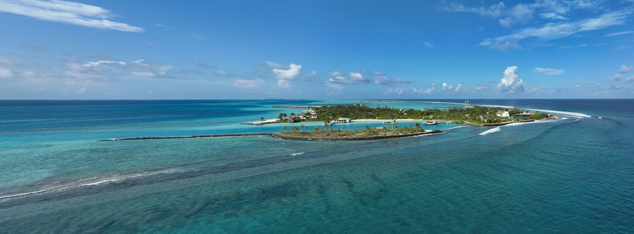 Aerial view of a serene island fringed by turquoise waters, showcasing a vibrant contrast between the lush greenery and the clear blue sky, Thulusdhoo, Kaafu Atoll, Maldives.
