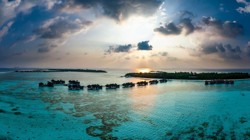 Maldives, North Male Atoll, Lankanfushi, Aerial view of Indian Ocean at sunset with tourist resort bungalows in background