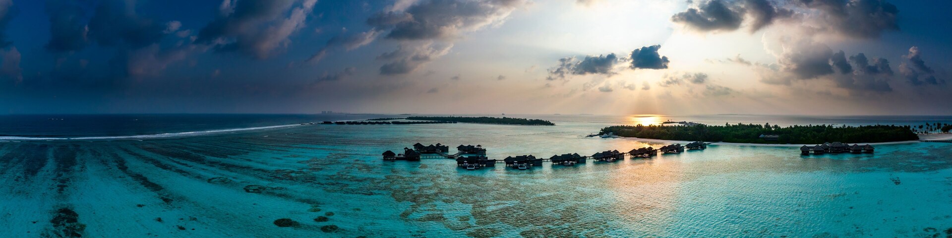 Una isla tropical con bungalós sobre el agua y un mar turquesa cristalino.