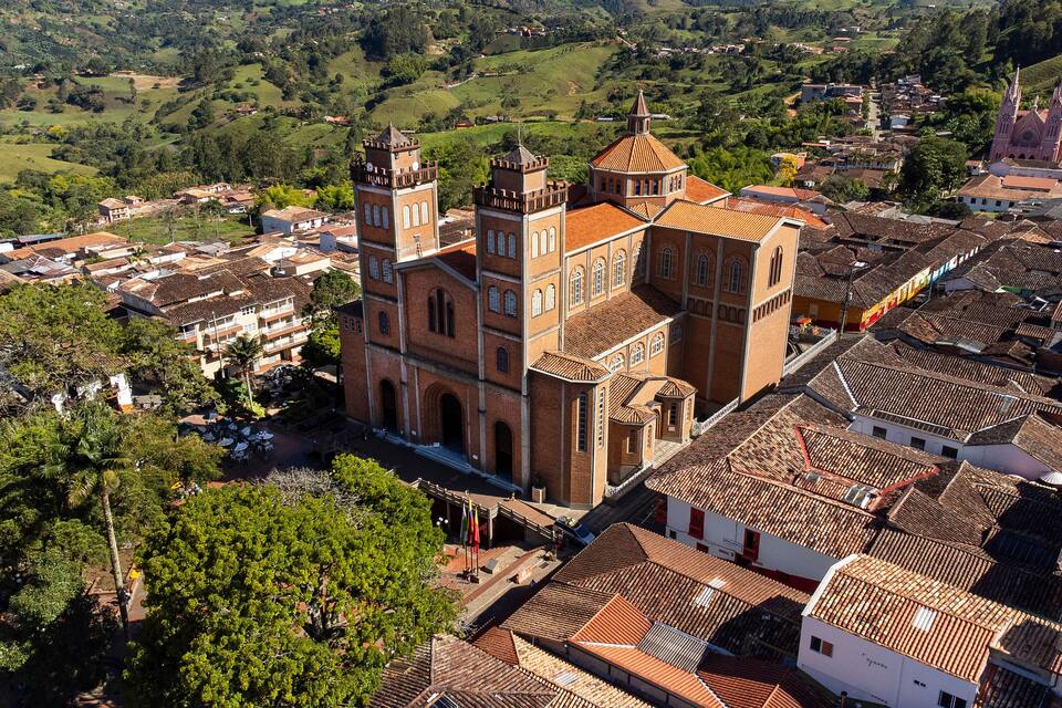 A historic church with a clock tower, surrounded by terraced houses and lush greenery.