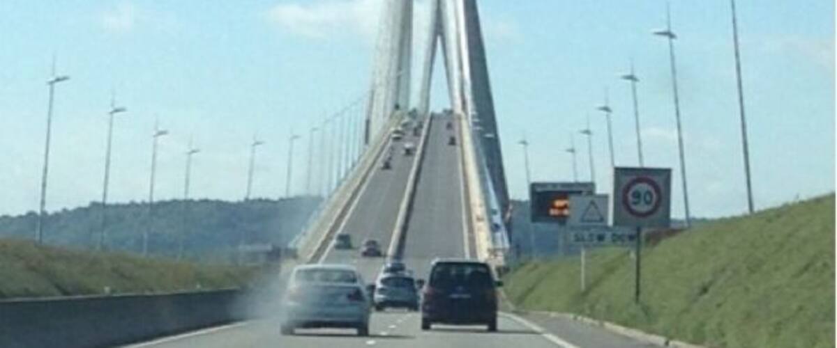 A bridge with tall towers and a road with cars.