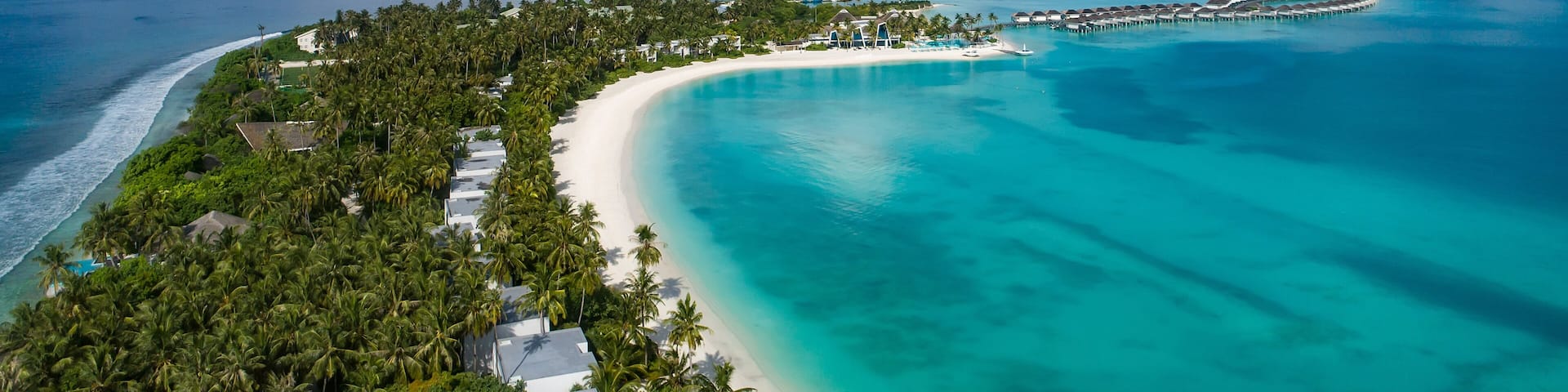 A tropical island with a white sandy beach, turquoise waters, and lush greenery.