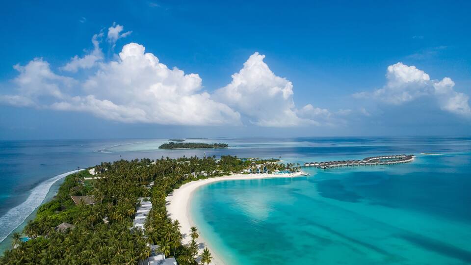 A tropical island with a white sandy beach, turquoise waters, and lush greenery.