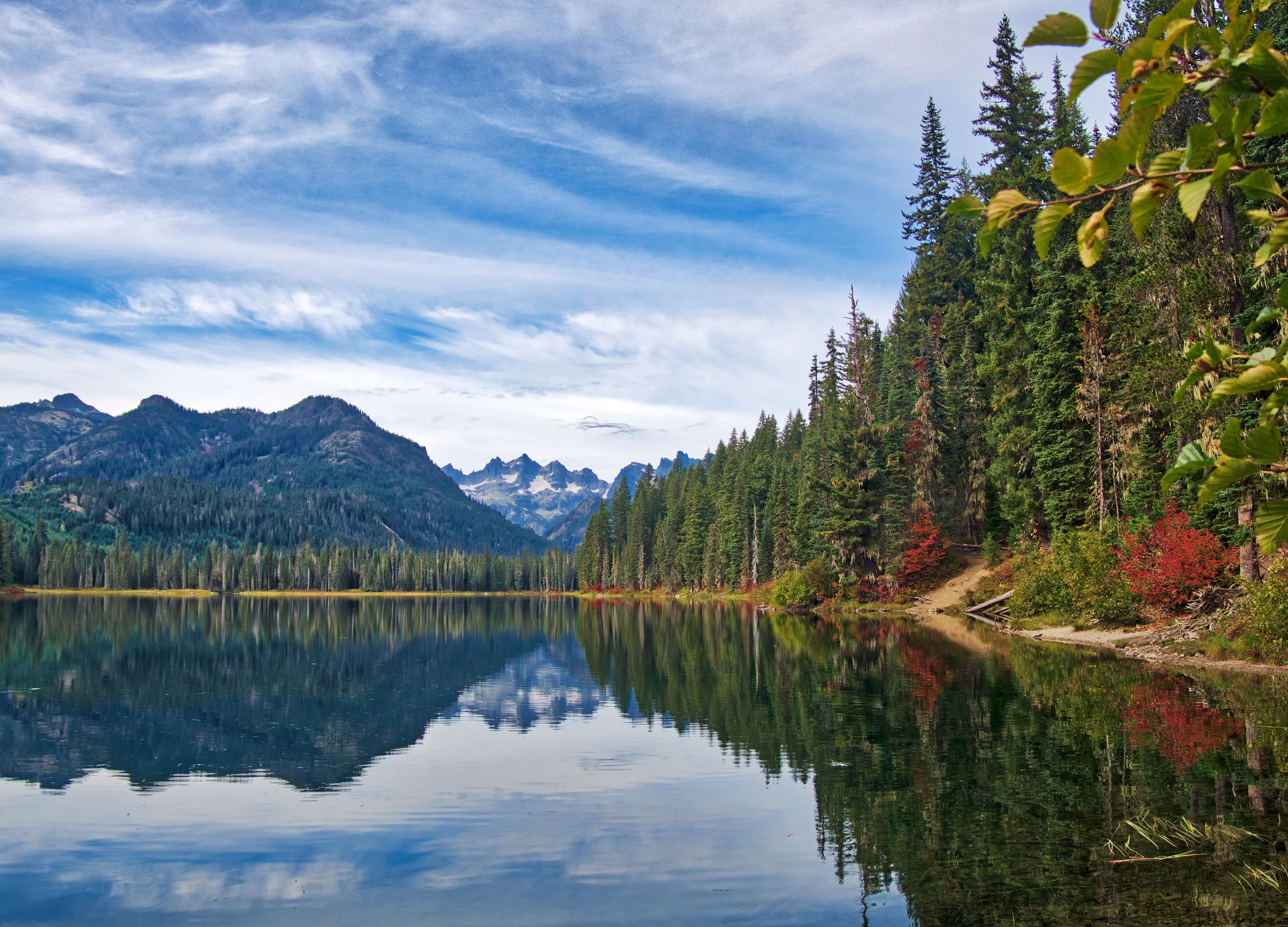 A calm lake reflecting mountains and trees.
