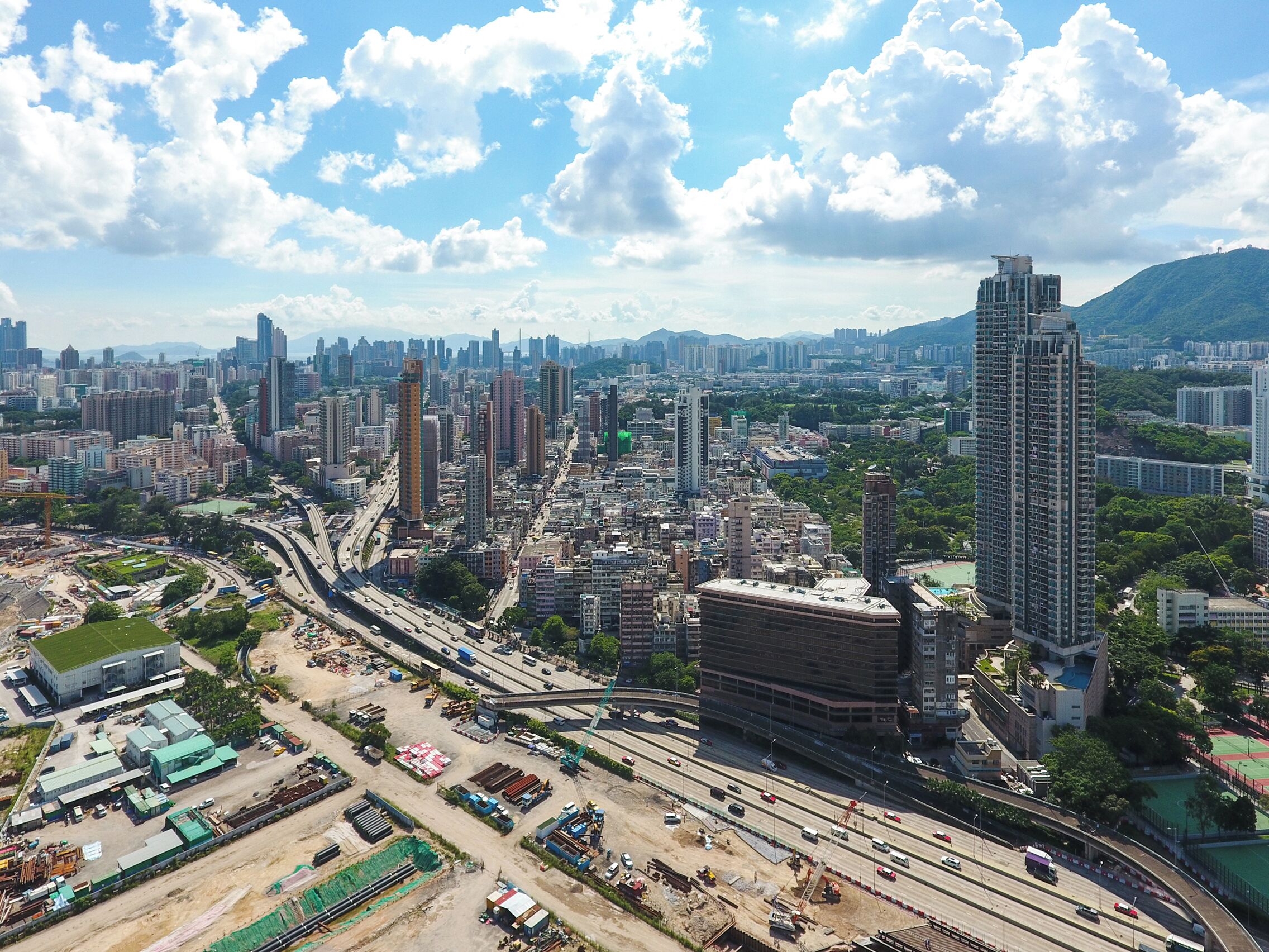 A cityscape with a mix of high-rise buildings, a highway, and construction sites.