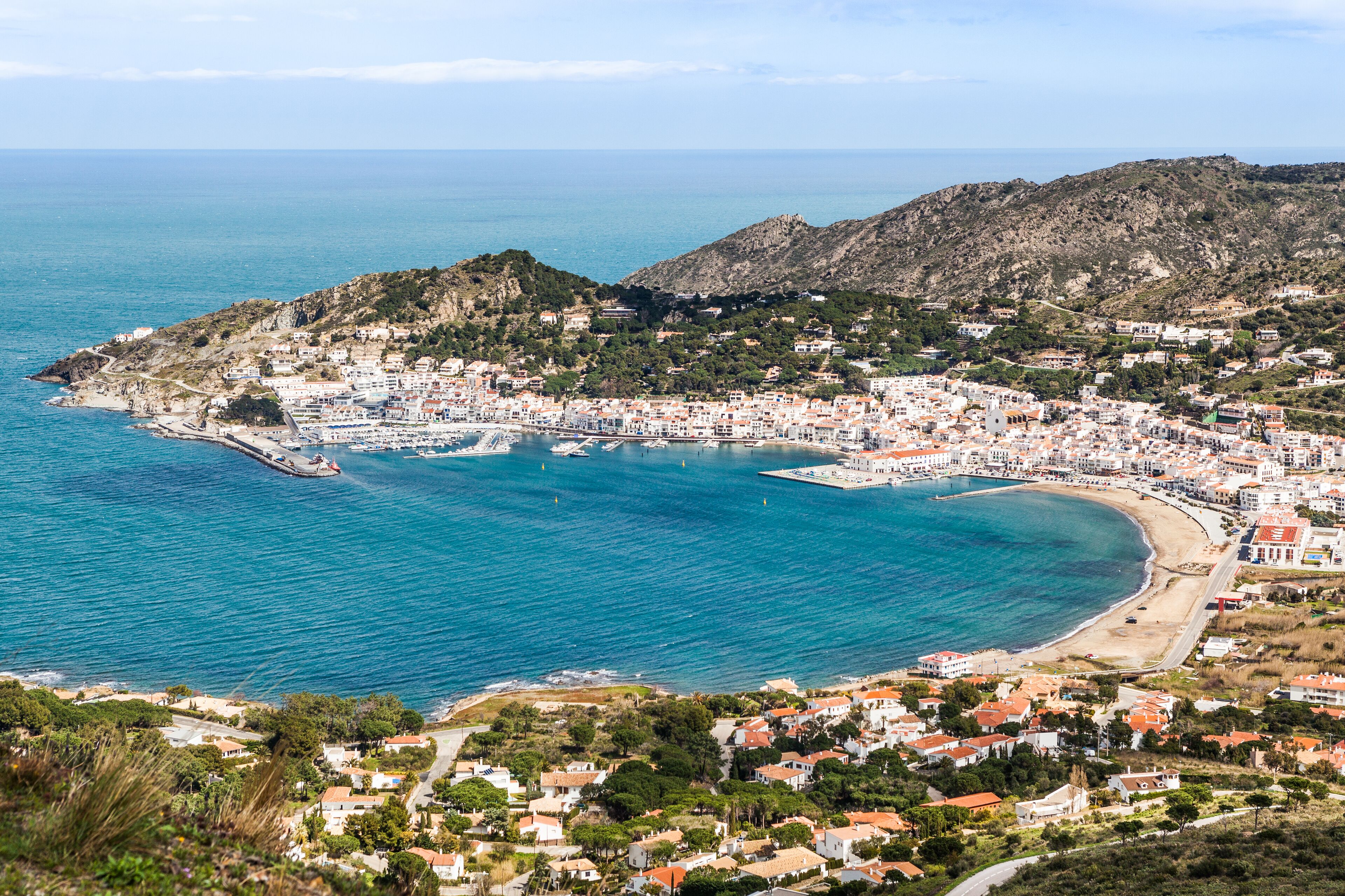 A coastal town with a bay, buildings, and a mountainous backdrop.