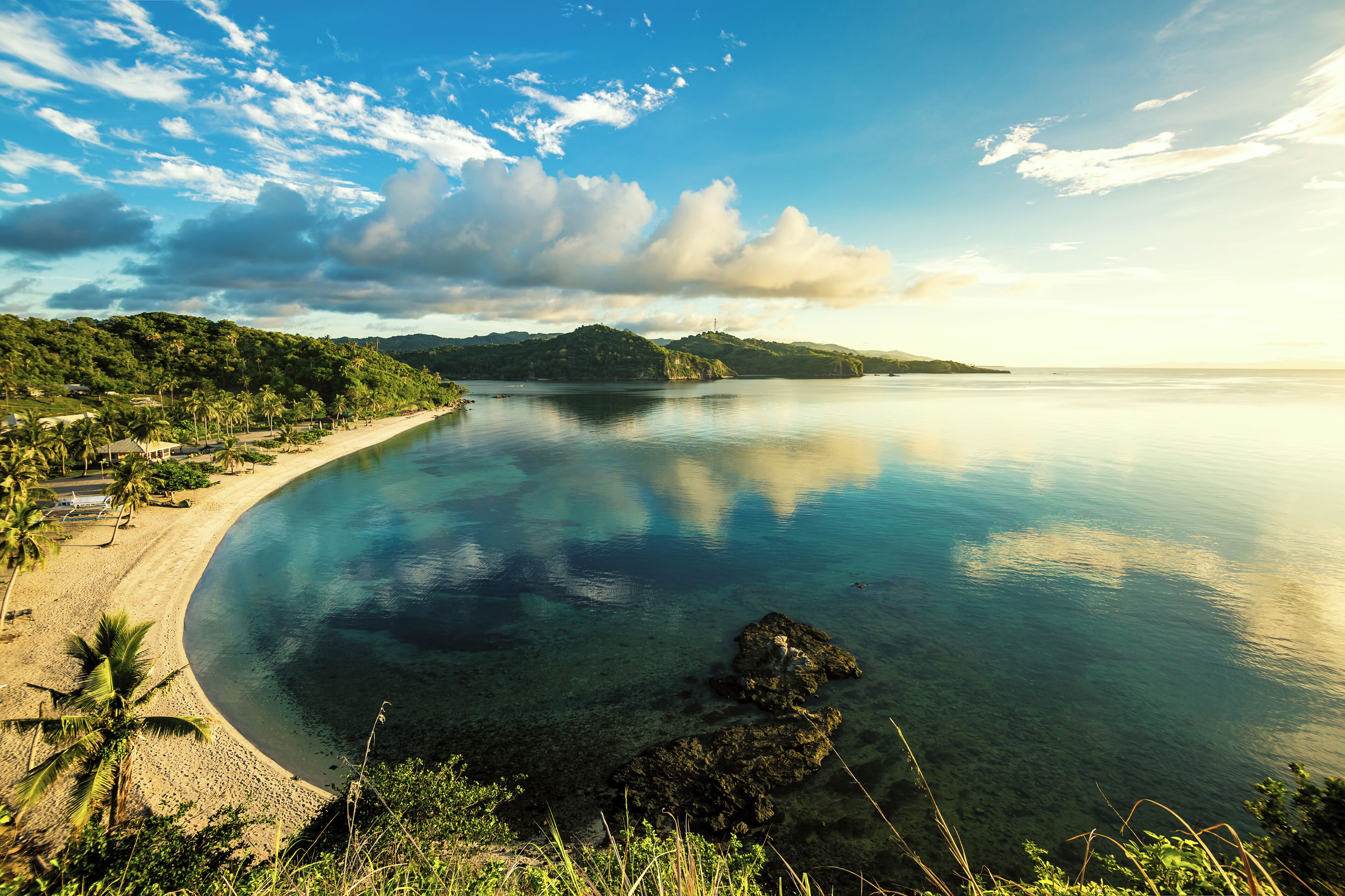 Woke up for this magnificent early morning view overlooking Aglicay Beach in Alcantara, Romblon, Philippines. The sun was just rising from the east and cast the scene in soft, warm colors; the clear and calm sea reflecting the clouds and the blue of the sky.