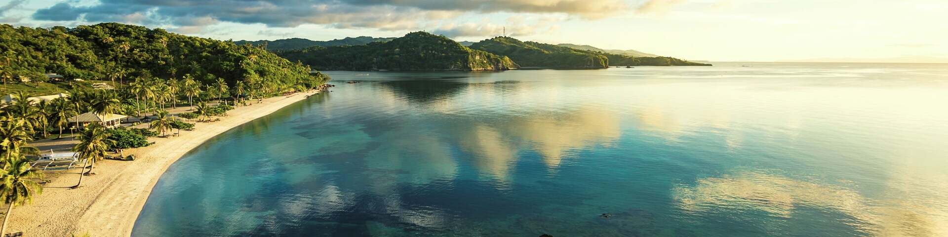 Woke up for this magnificent early morning view overlooking Aglicay Beach in Alcantara, Romblon, Philippines. The sun was just rising from the east and cast the scene in soft, warm colors; the clear and calm sea reflecting the clouds and the blue of the sky.