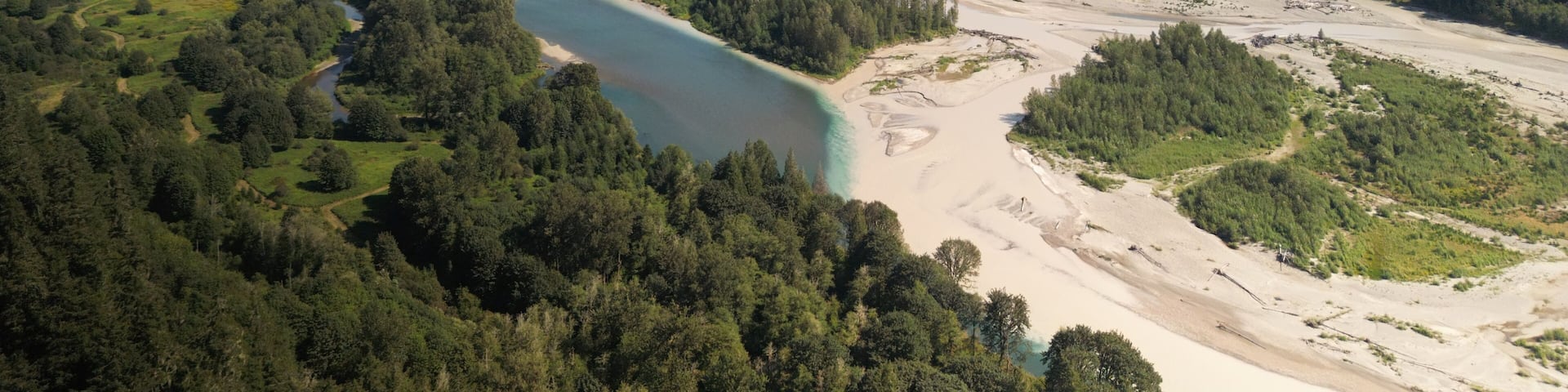 A river winding through a forested valley with mountains in the background.