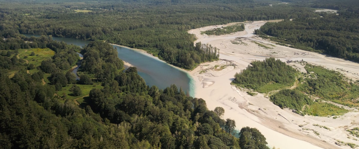 A river winding through a forested valley with mountains in the background.