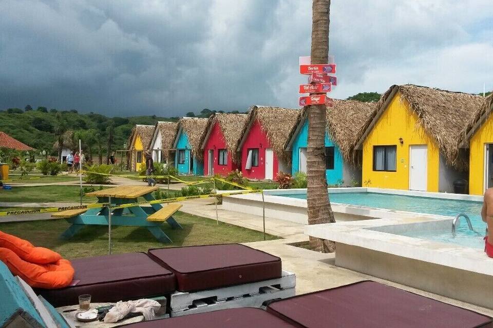 Des huttes aux toits de chaume aux couleurs vives, une piscine et un paysage tropical.