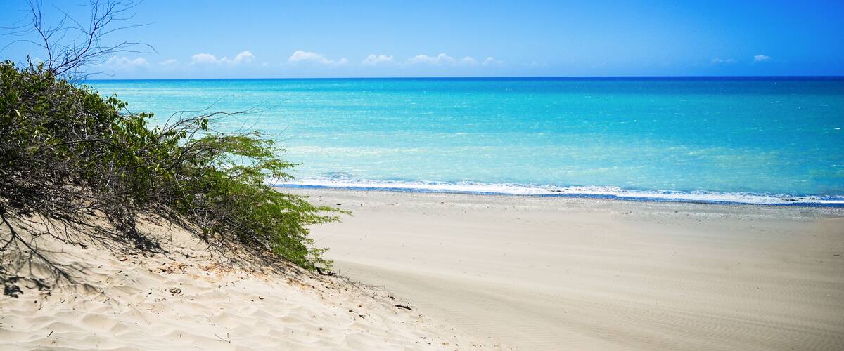 A beach with clear turquoise water and a sandy shore.