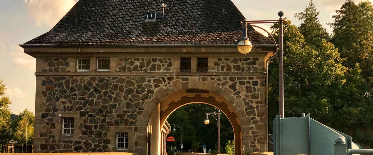 A stone building with a tiled roof and an arched entrance.