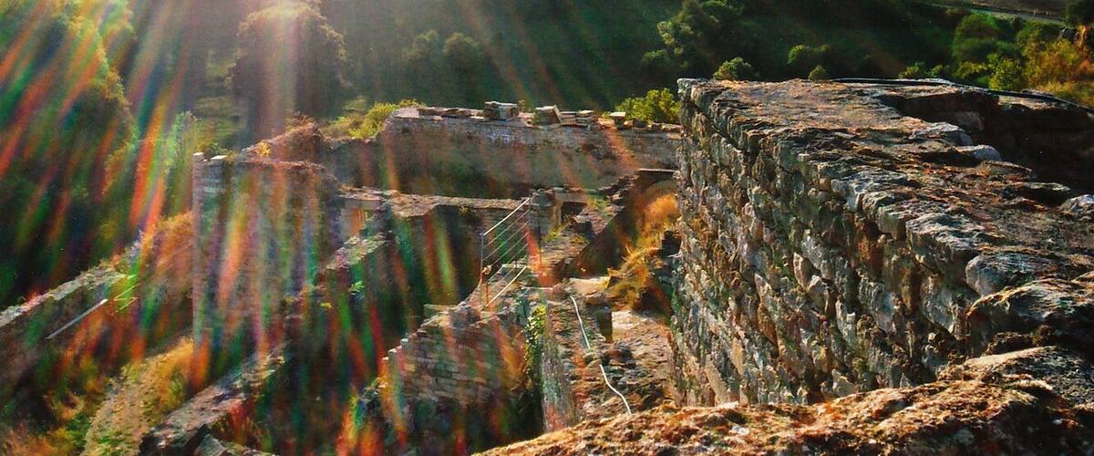 A historical stone structure with a view of rolling hills and a distant road.