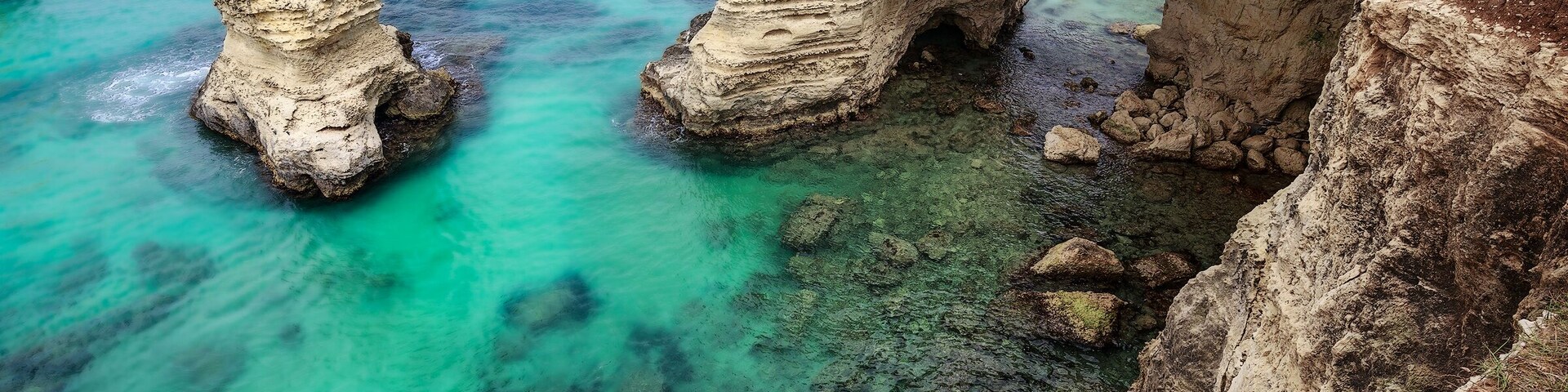 Torre Sant'Andrea is a small town on the Adriatic coast of Salento. It 'a very small and ancient fishing village that is located where the coast is slightly higher.
The extraordinary nature of its coast and its sea, make it an unforgettable destination. The coastline is, in fact, remained almost untouched and looks ragged, full of ravines and caves, the protrusions and recesses and large isolated rocks in the sea, real stacks.
What amazes the eye is the presence of these magnificent rocks rising from crystal clear that water ... The sea erosion has created in this place something truly magical. High cliffs stand not far from the coast and look like giant guarding the territory.
The most beautiful cliff is shaped like a arch: swim under this rock is a unique experience that can only be done in some corners of the world.
If you're ever in the right day, you will find calm and crystalline water that will never forget. The color of the sea, in fact, goes from light green to emerald green, revealing an extraordinary backdrop.