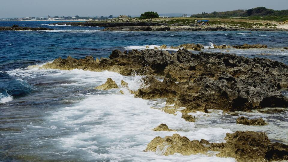 A rocky coastline with waves crashing against the shore.