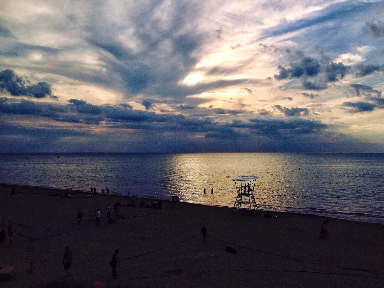 A beach at sunset with a lifeguard tower and people in the distance.
