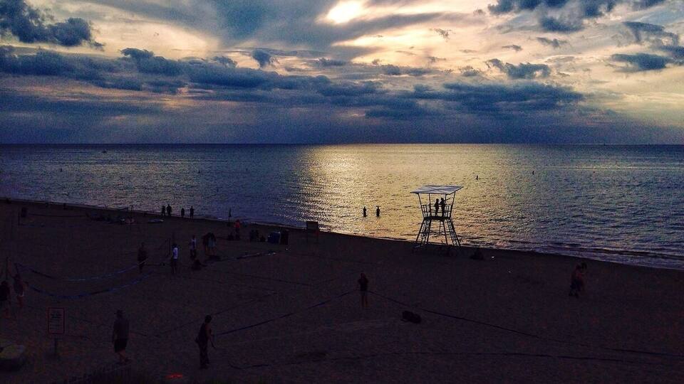 A beach at sunset with a lifeguard tower and people in the distance.