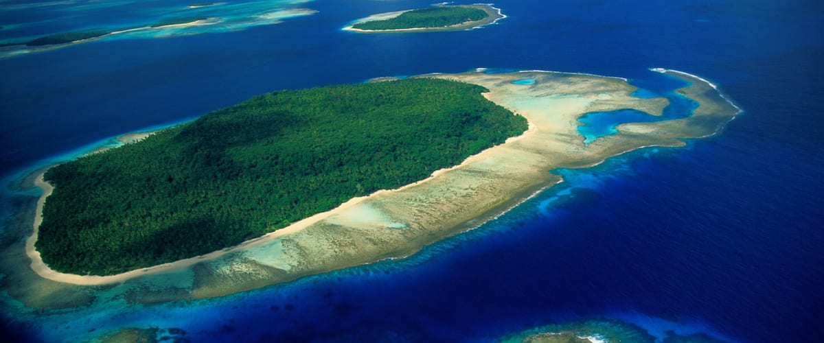 An aerial view of a chain of islands with clear blue waters and sandy beaches.