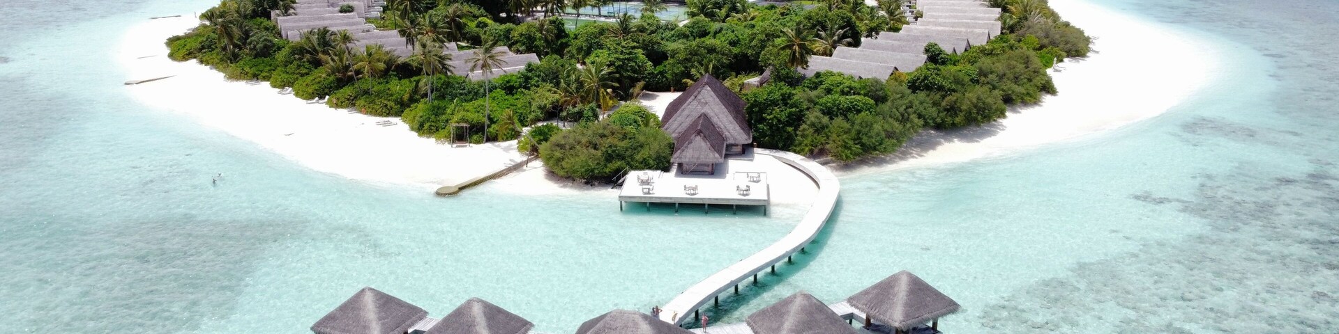 An overwater bungalows on a small island surrounded by turquoise waters.