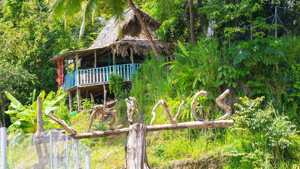 Panama, Chiriqui province, Limones welcome sign made from tree trunks, and jungle hut