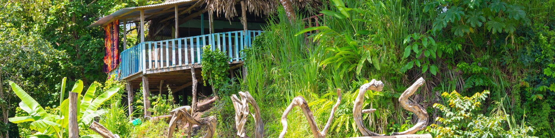 Panama, Chiriqui province, Limones welcome sign made from tree trunks, and jungle hut