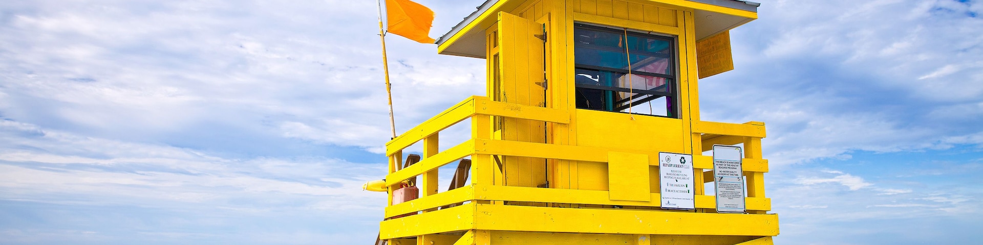 Una torre de salvavidas amarilla en una playa con el océano al fondo.