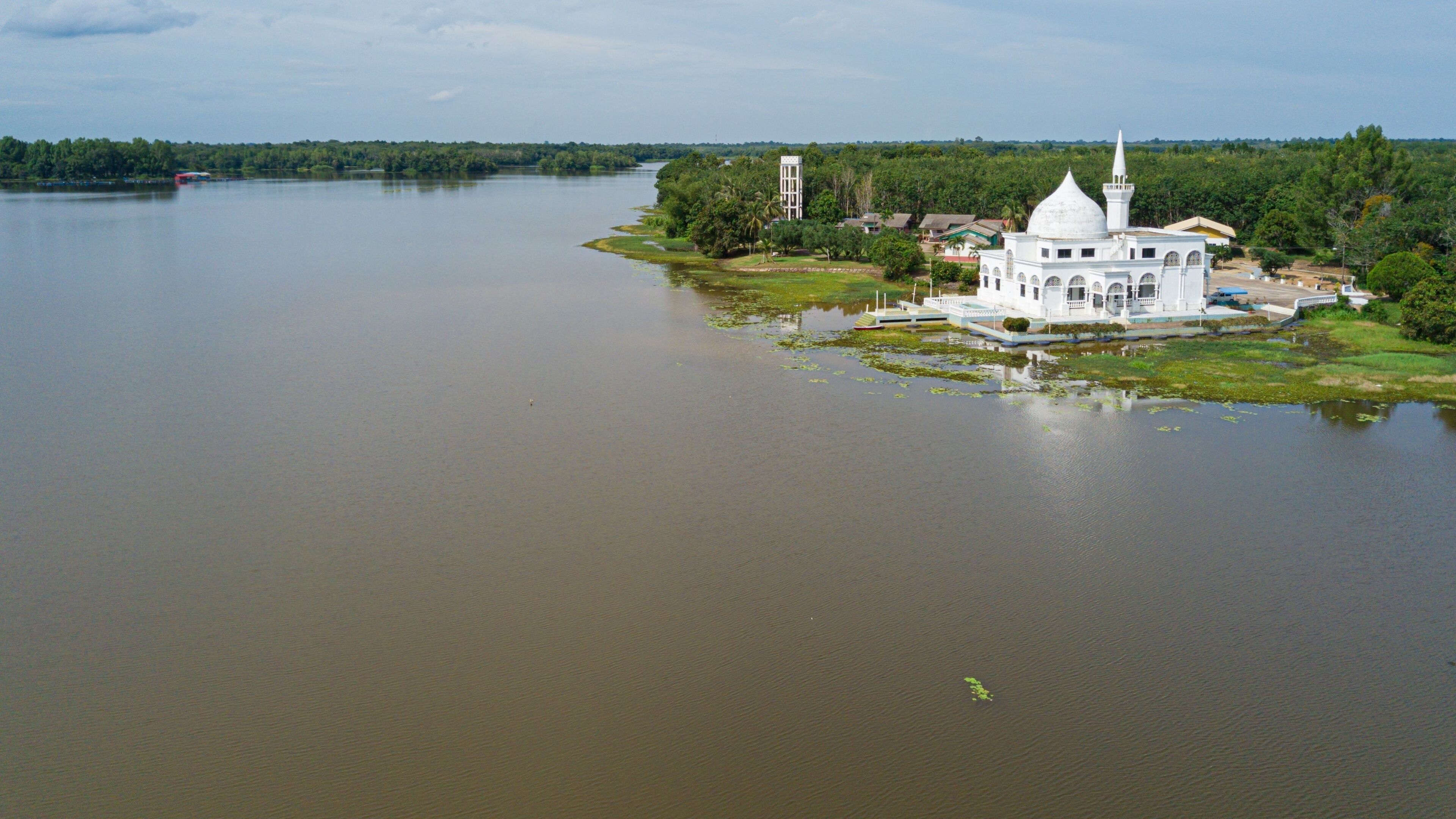 Drone shot of a white mosque by a lake at Danau Tok Uban, Tanah Merah, Kelantan, Malaysia.
