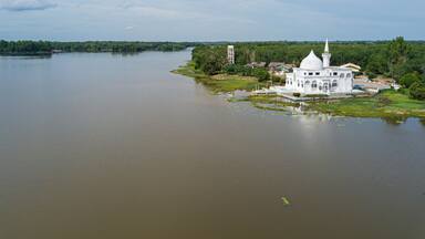 Drone shot of a white mosque by a lake at Danau Tok Uban, Tanah Merah, Kelantan, Malaysia.