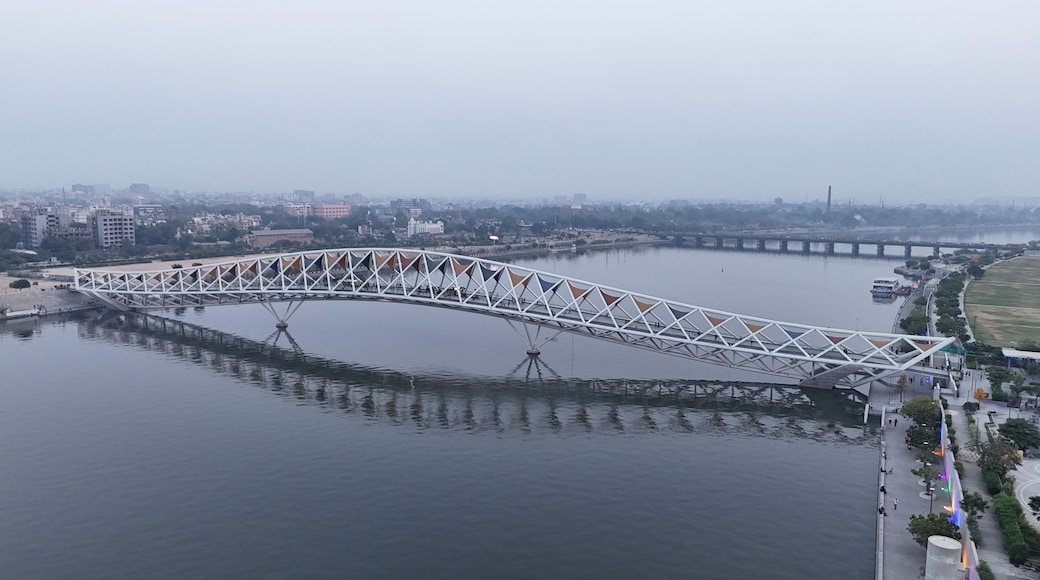 A large white bridge over a river with a cityscape in the background.
