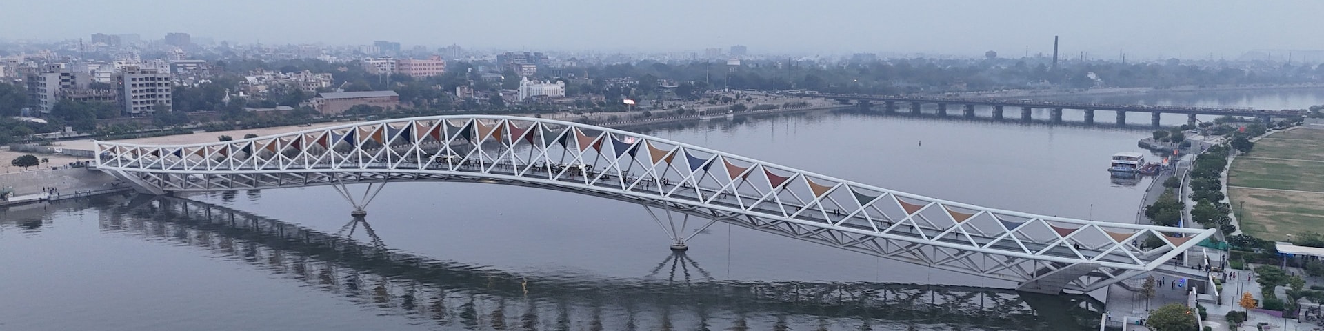 Uma grande ponte branca sobre um rio, com um horizonte urbano ao fundo.