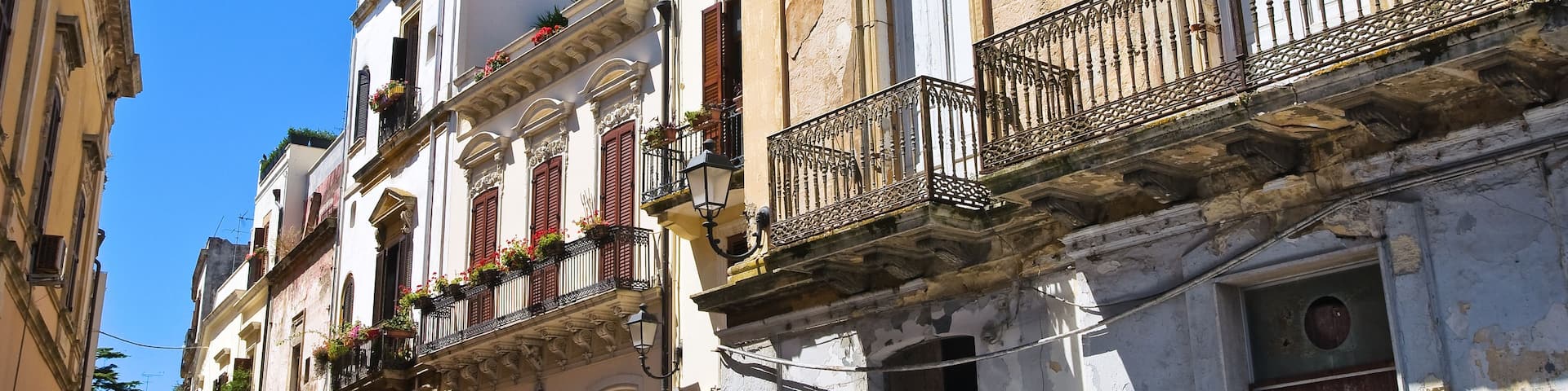 A row of historic buildings with ornate balconies and flower boxes.