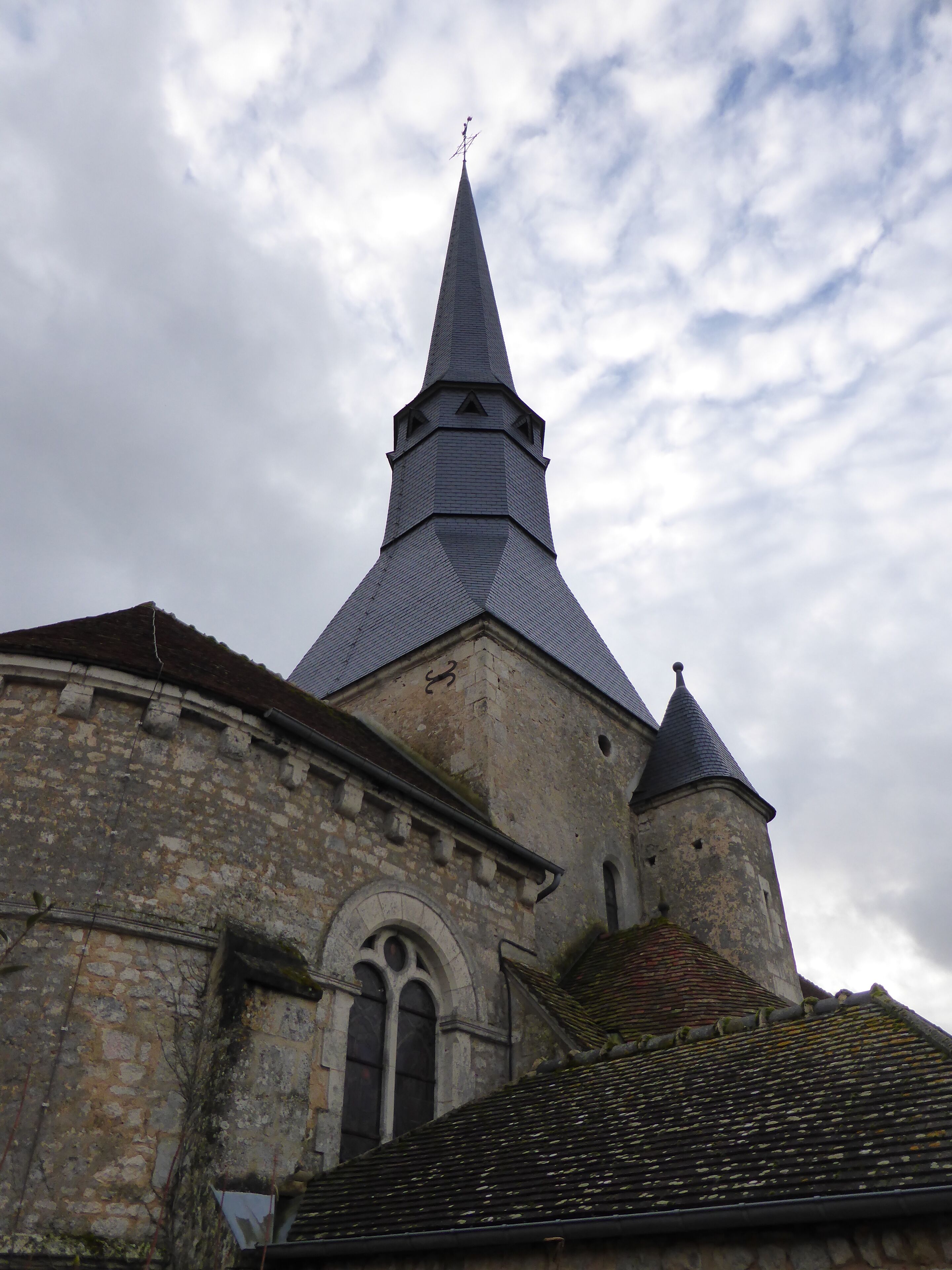 A church with a tall, pointed steeple and a stone building with a rounded arch window.