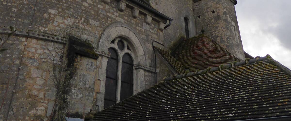 A church with a tall, pointed steeple and a stone building with a rounded arch window.