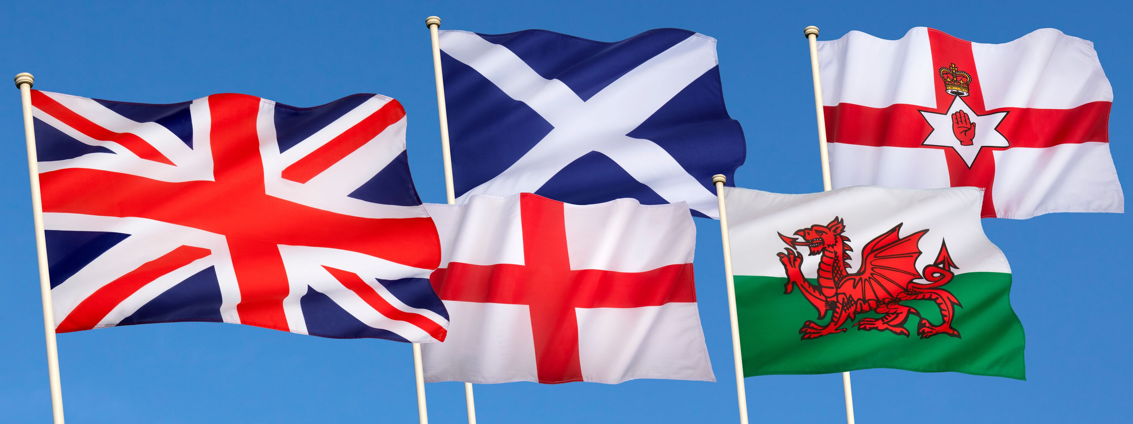 Five flags waving against a clear blue sky.