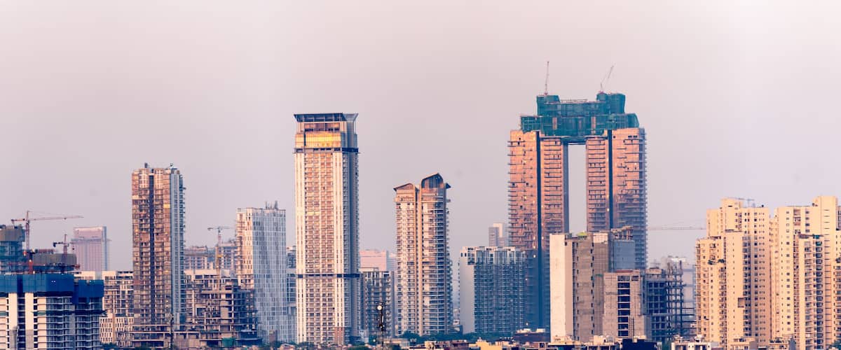 Aerial drone shot showing high rise skyscrapers under construction and completed cityscape of gurgaon delhi noida at dusk with sunlight reflected in India