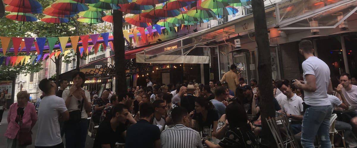 A crowded outdoor area with colorful umbrellas hanging overhead.