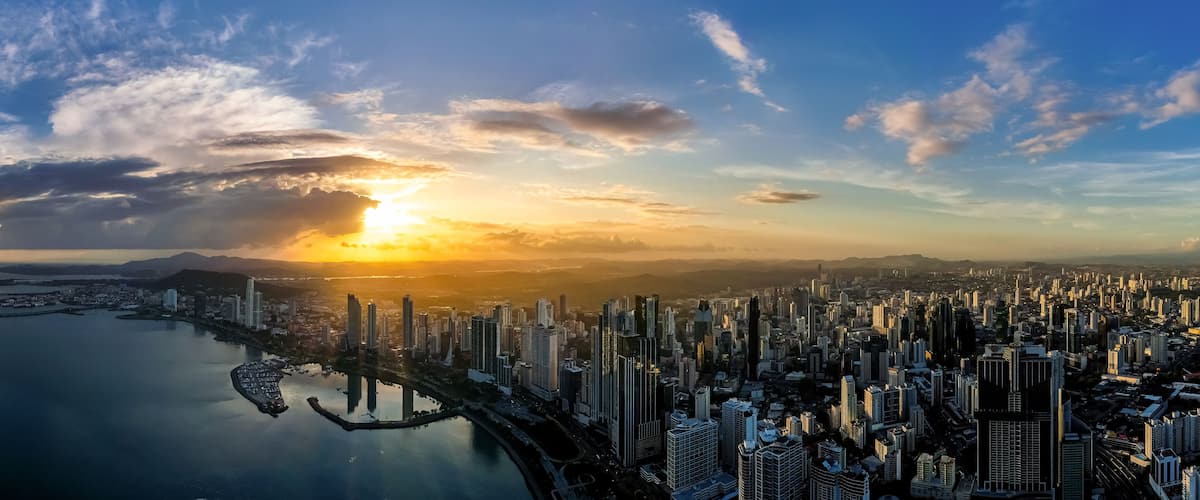 Un paysage urbain côtier avec un coucher de soleil, des immeubles de grande hauteur et une marina.