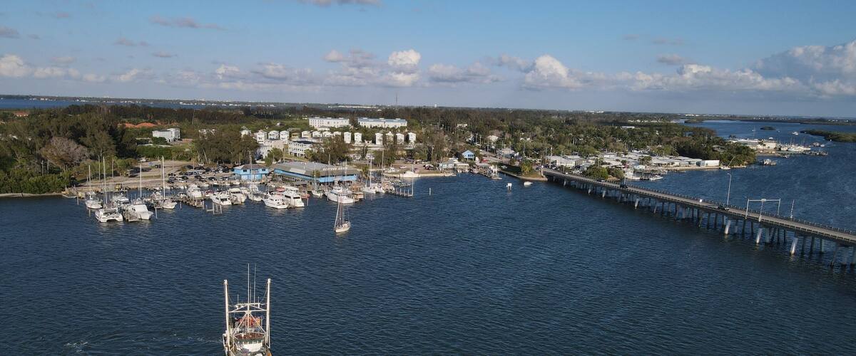 A coastal town with a marina, a bridge, and a green boat in the water.