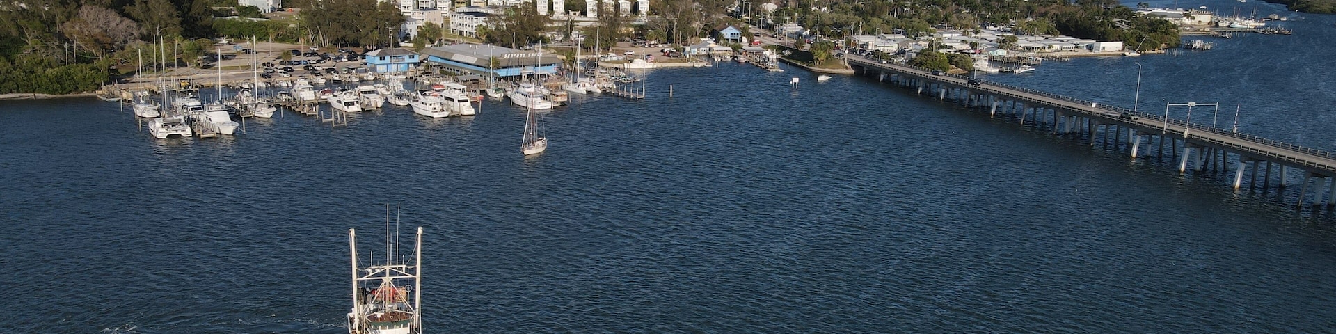 A coastal town with a marina, a bridge, and a green boat in the water.